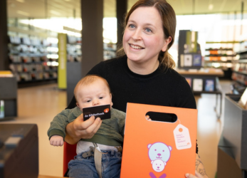 Moeder met het BoekStartkofferte, haar baby en een lidmaatschapspas van de Bibliotheek