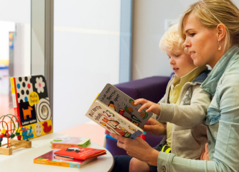 moeder met haar baby leest een boekje van de bieb
