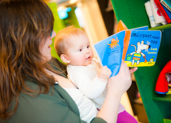 moeder met baby en boekje in de bibliotheek