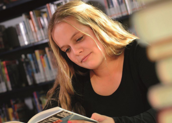 tienermeisje leest boek in de bibliotheek